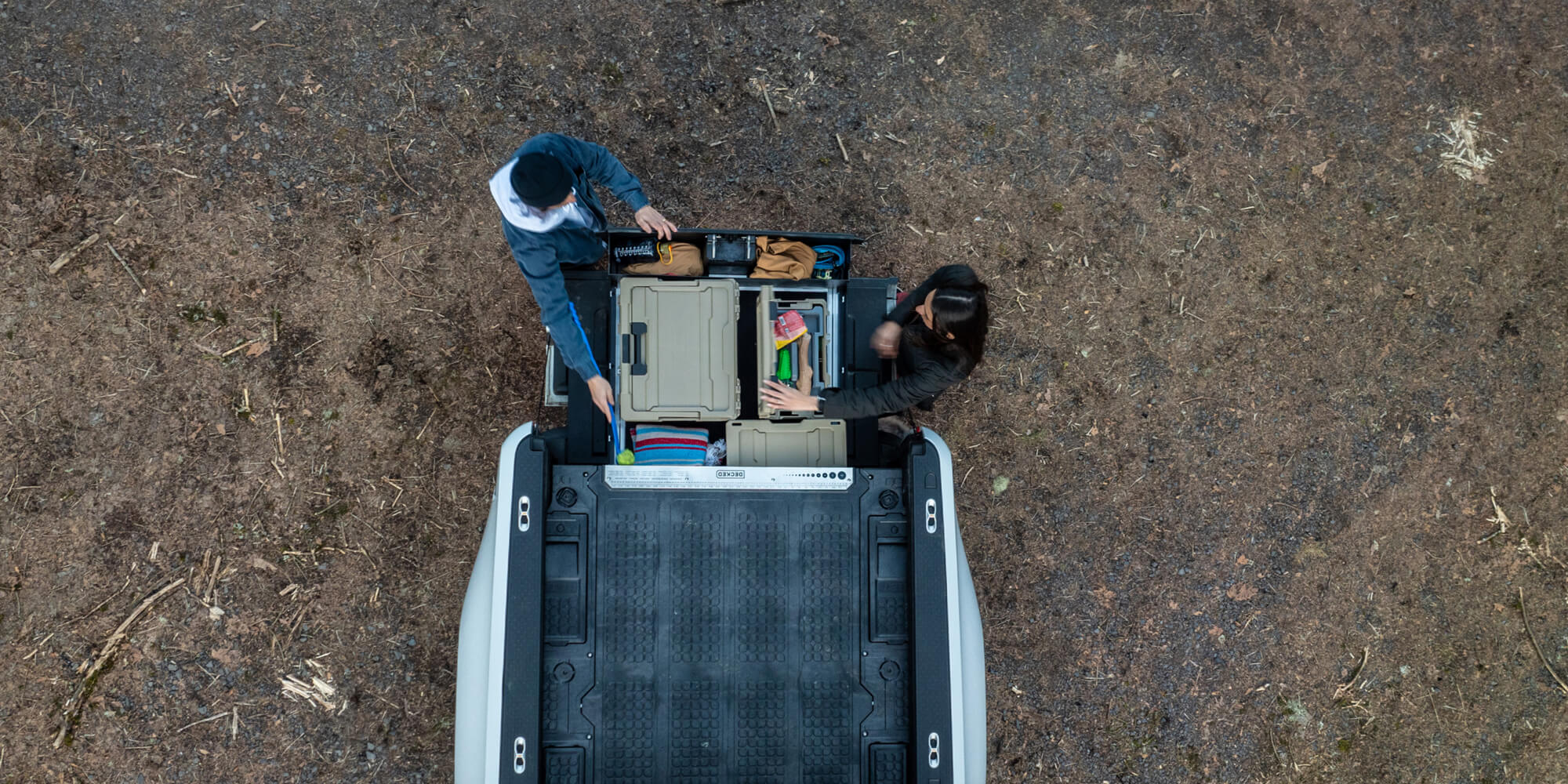 A couple retrieving gear from his Rivian Drawer System to play fetch with their dog.