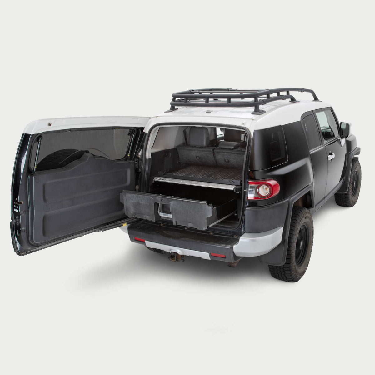A Toyota FJ Cruiser on a white background with a Drawer System installed in the cargo area. The Drawer System is extended and shows the interior storage space.