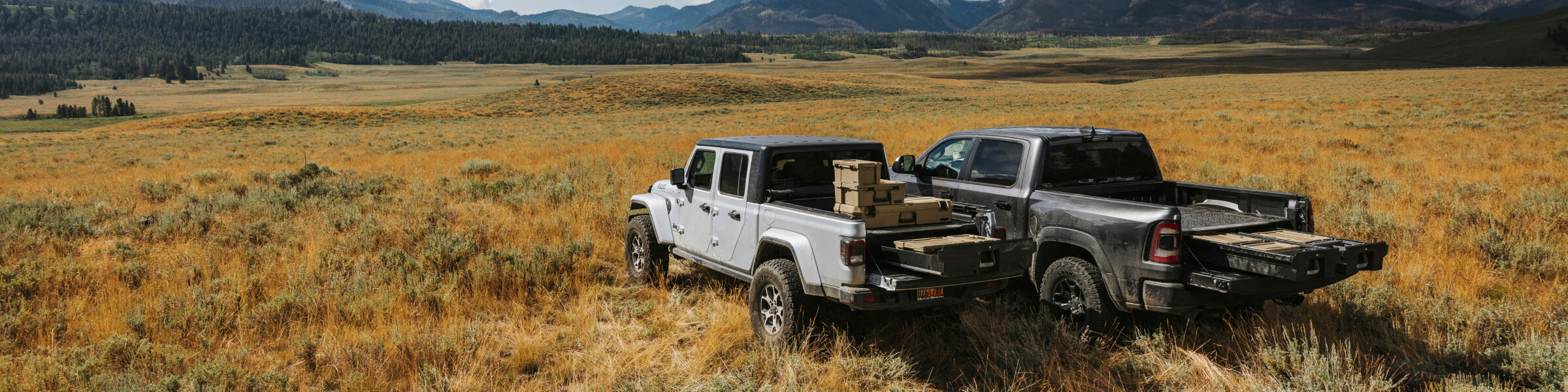 DECKED Drawers open up as wide as the open prairie. Pictured here with a midsized truck and a full-size truck, both outfitted with DECKED Drawer Systems, out among the sagebrush of the open range.