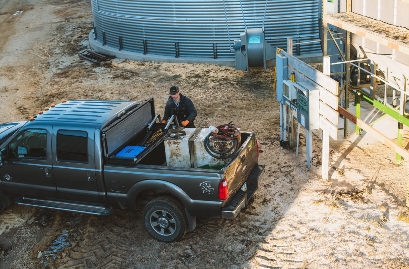 Truck with decked tool box in the back open and a man standing next to it