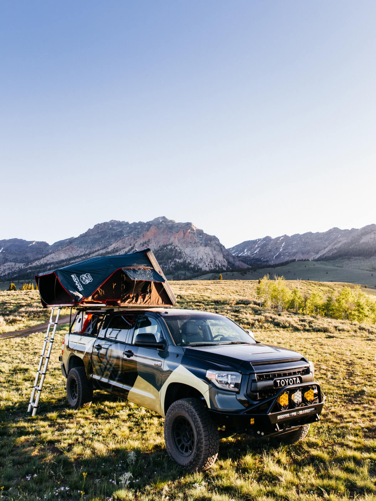 Truck in the mountains with a pickup truck tent open for camping