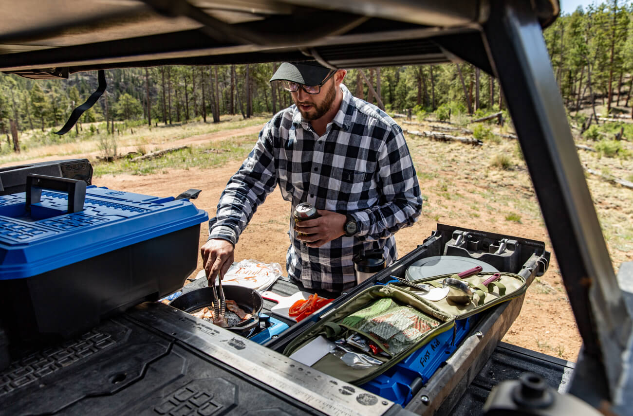 man cooking dinner on the back of his truck with one drawer open