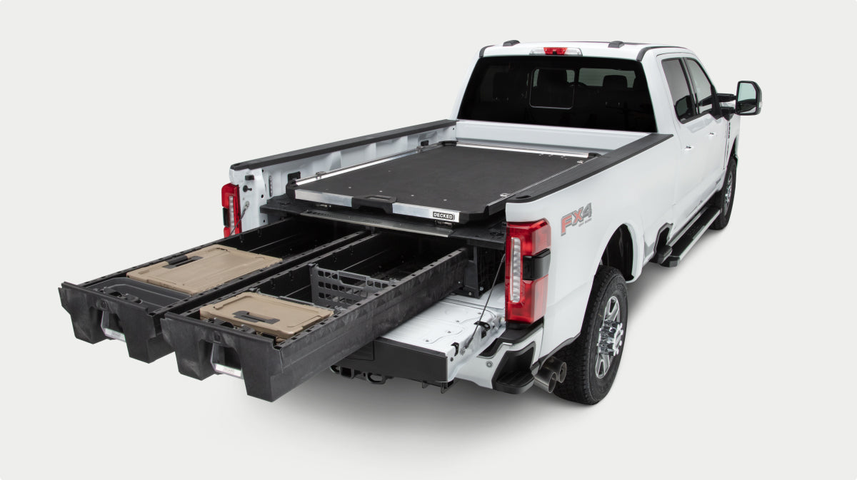 A white pickup truck shown from the rear three-quarter angle on a light gray studio background, with a Drawer storage system, CargoGlide and bins extended from the bed.