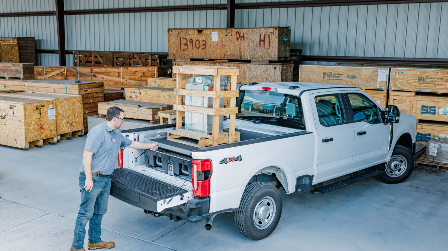 White pickup truck with a man interacting with the bed in a warehouse setting
