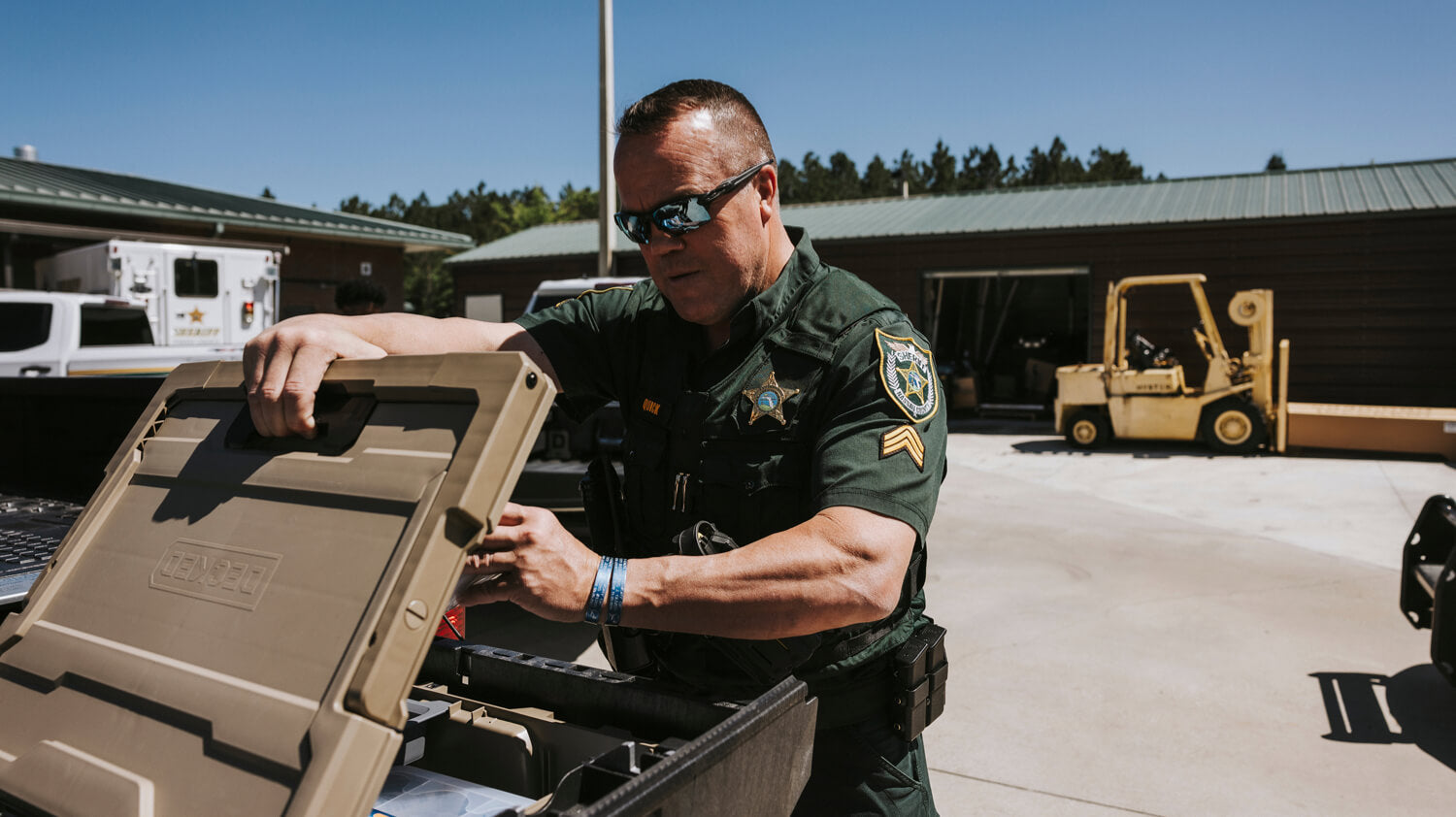 Officer opening a Halfrack 32 protective case outdoors with a building and forklift in the background.