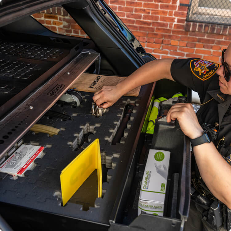 Person organizing items in a car trunk with a DECKED Drawer System for PIUs