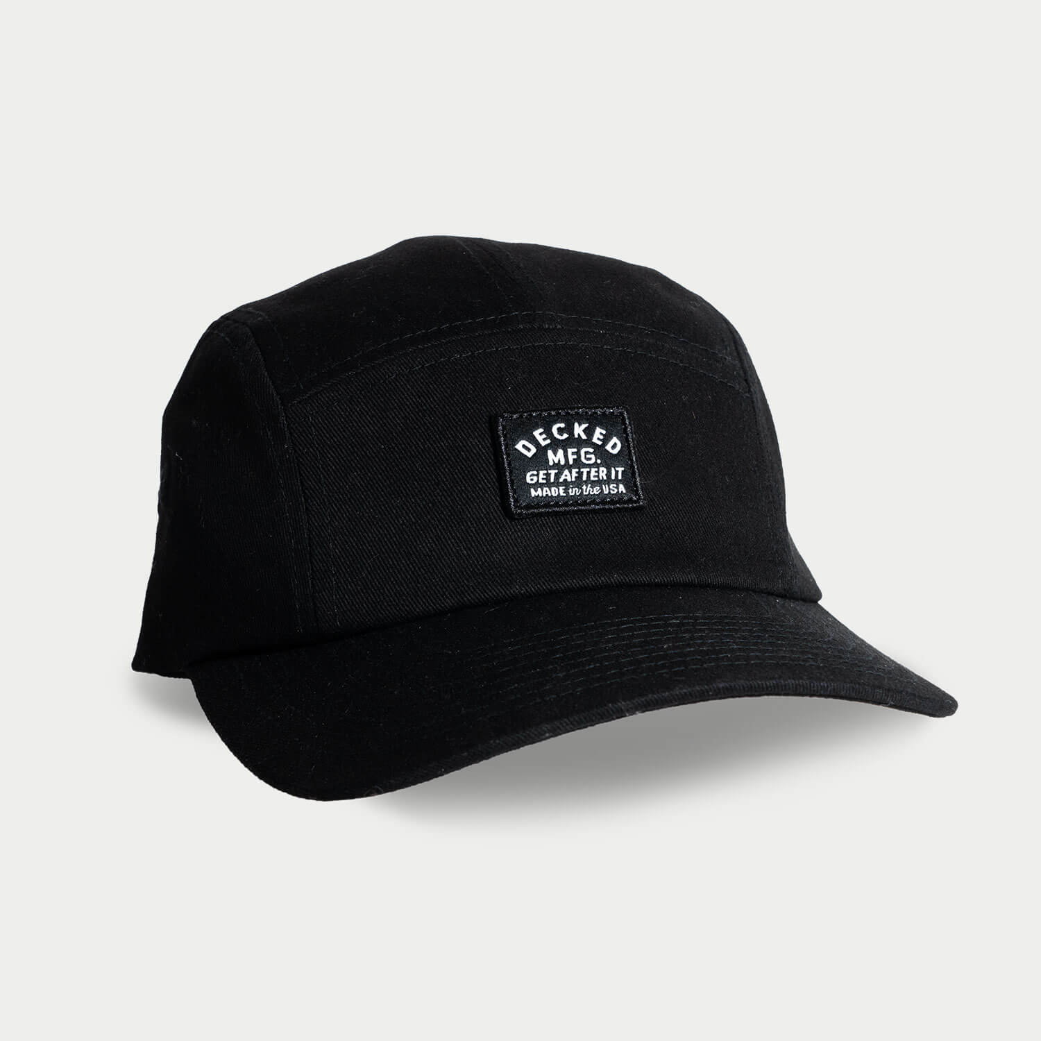 A black 5-panel hat that has a small DECKED patch that says GET AFTER IT and Made in the USA.