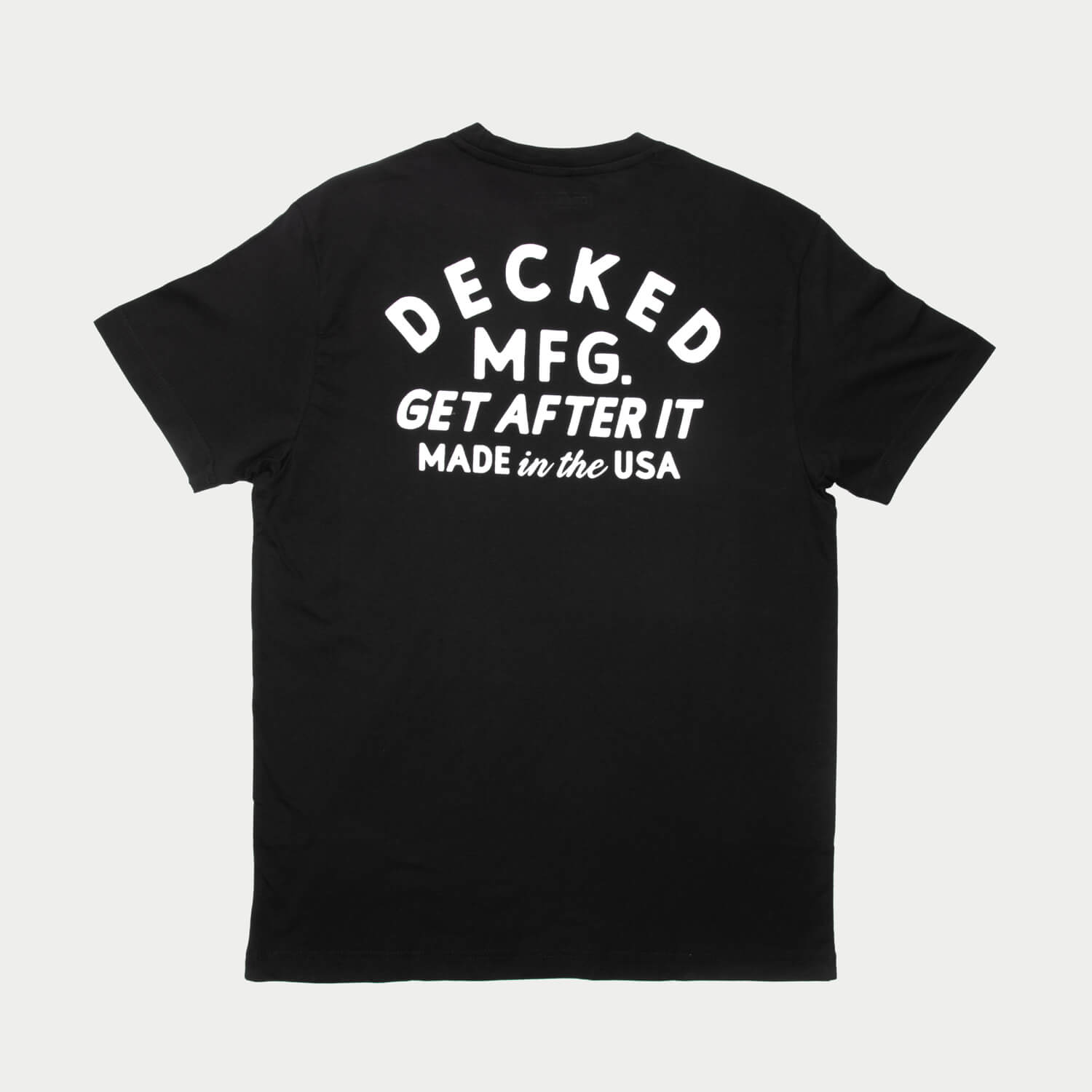 The back of a black t-shirt with a large logo that says DECKED MFG. the shirt is on a light gray background
