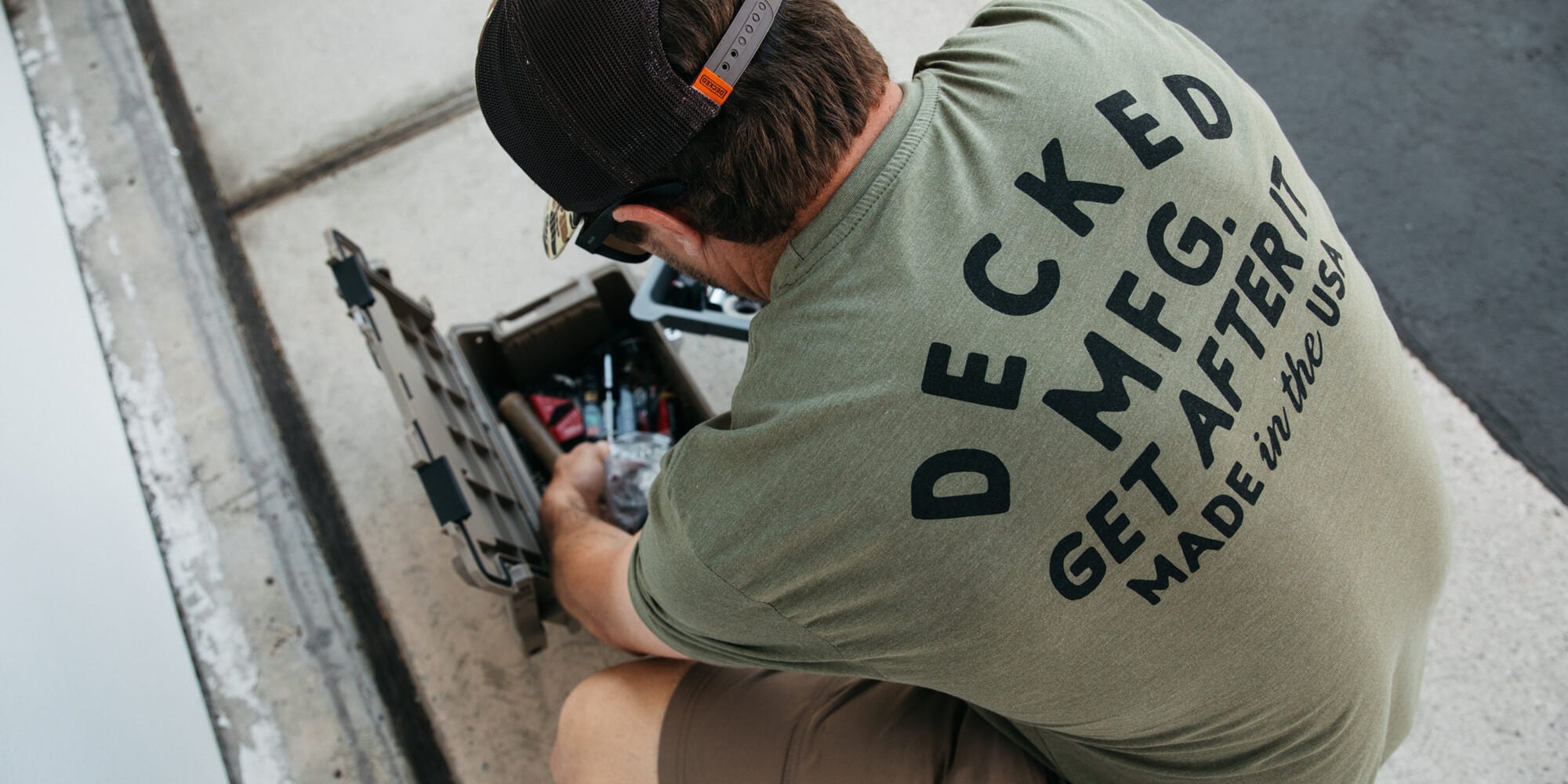 Person wearing a 'Decked MFG' t-shirt working on a skateboard.