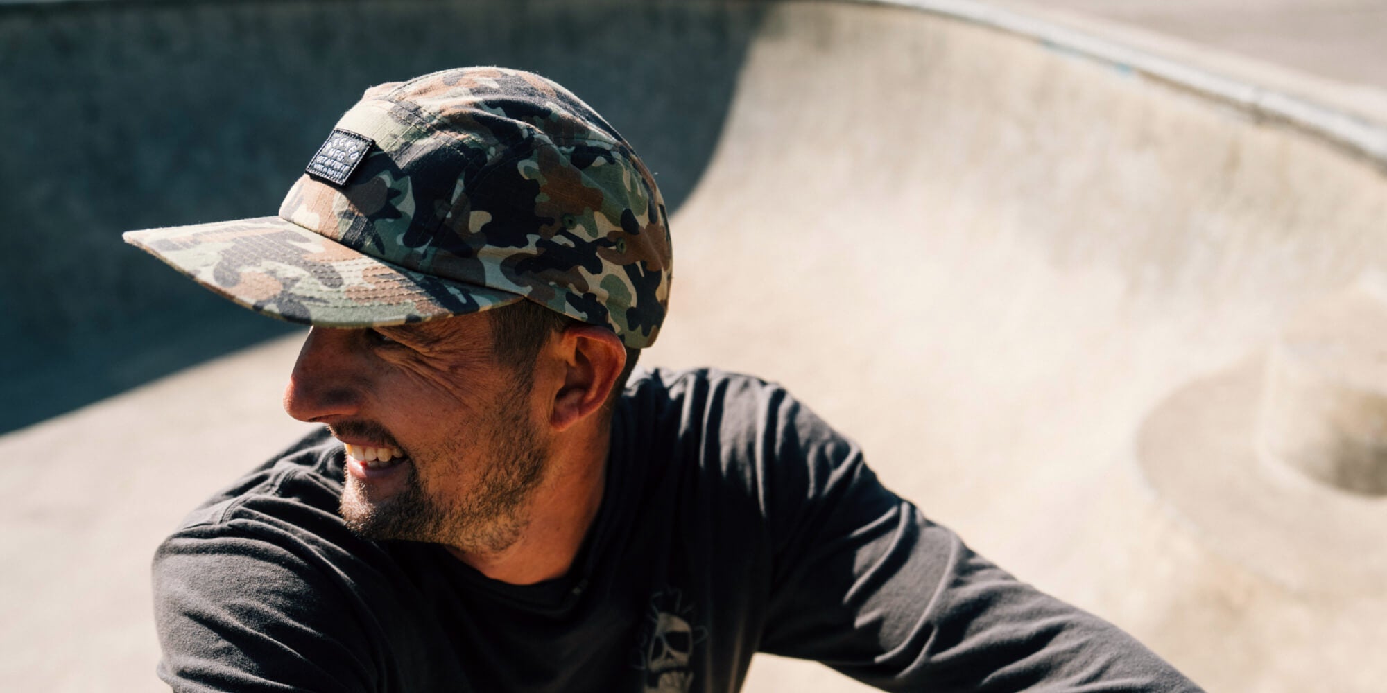 Man wearing a camouflage DECKED cap at a skate park