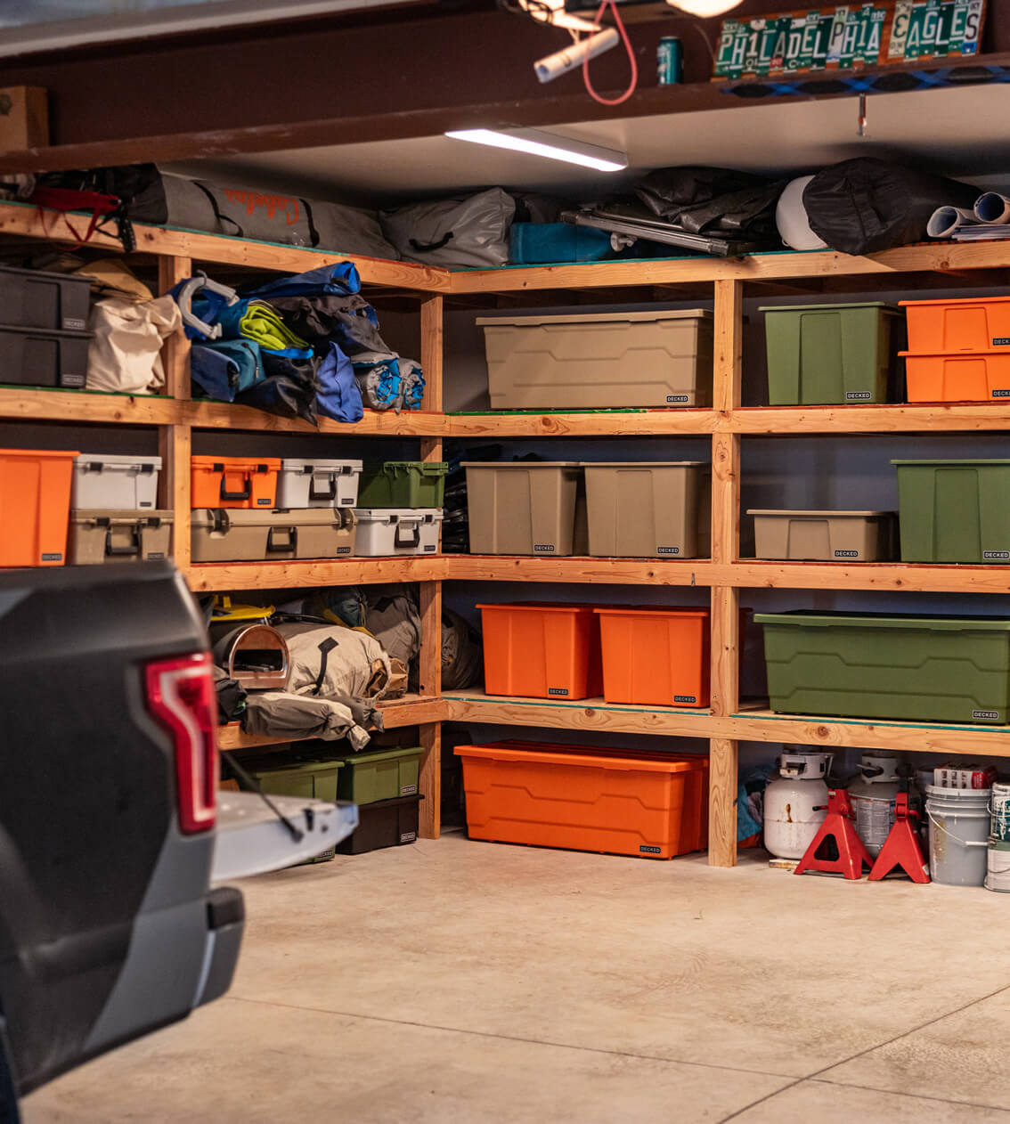 Storage room with shelves filled with various Payloader storage bins, protective cases and other items, including a truck partially visible.