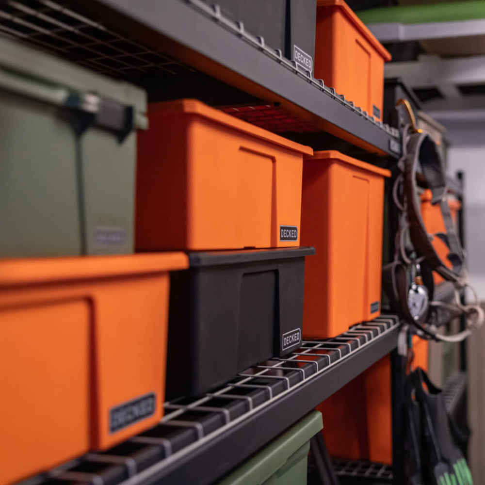 Orange, green and black Payloader storage bins on a metal shelf in a workshop setting