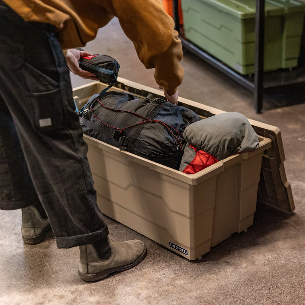 Person organizing camping gear into a large Payloader 133 storage container.