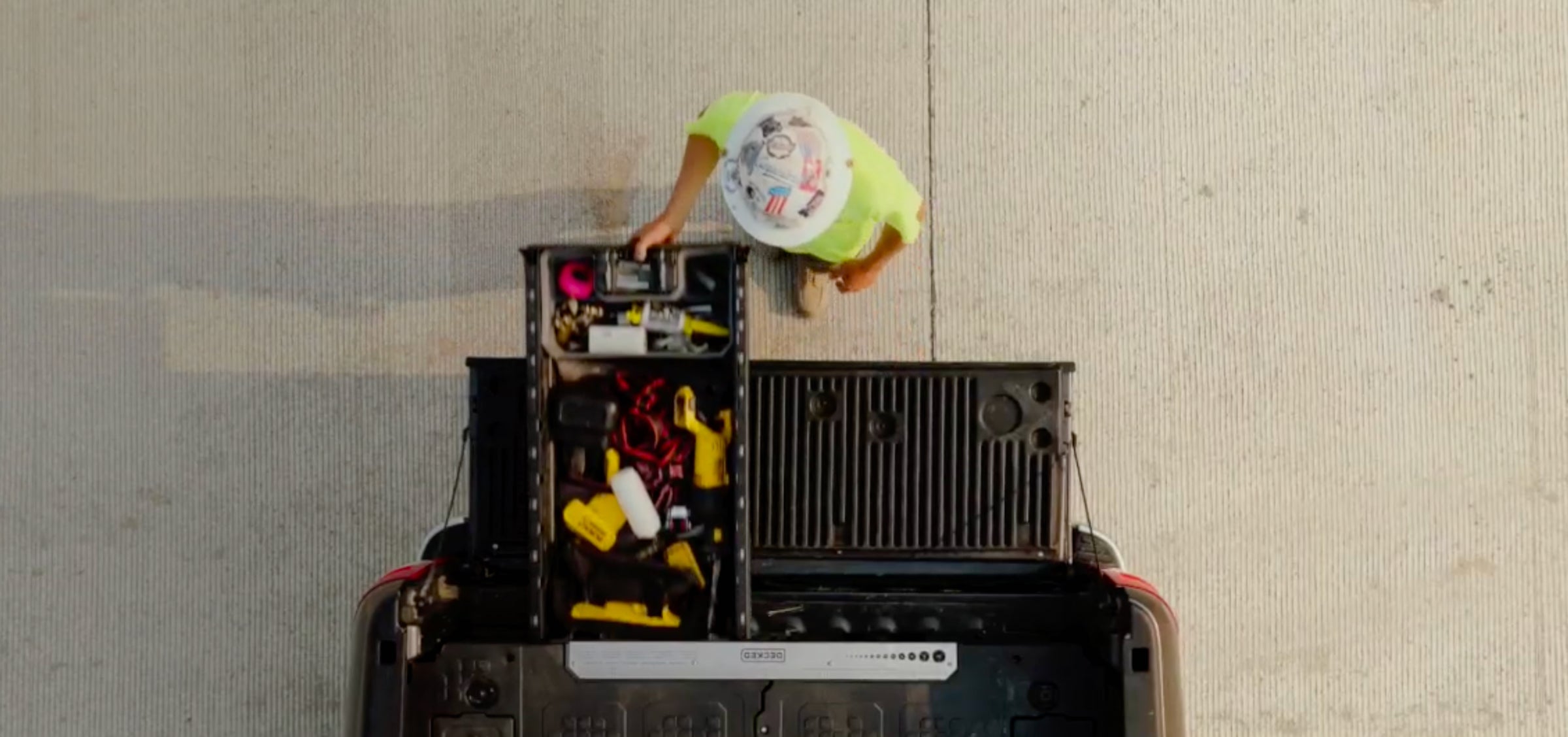 Person reaching into a DECKED Drawer System in the back of a truck bed at a jobsite.