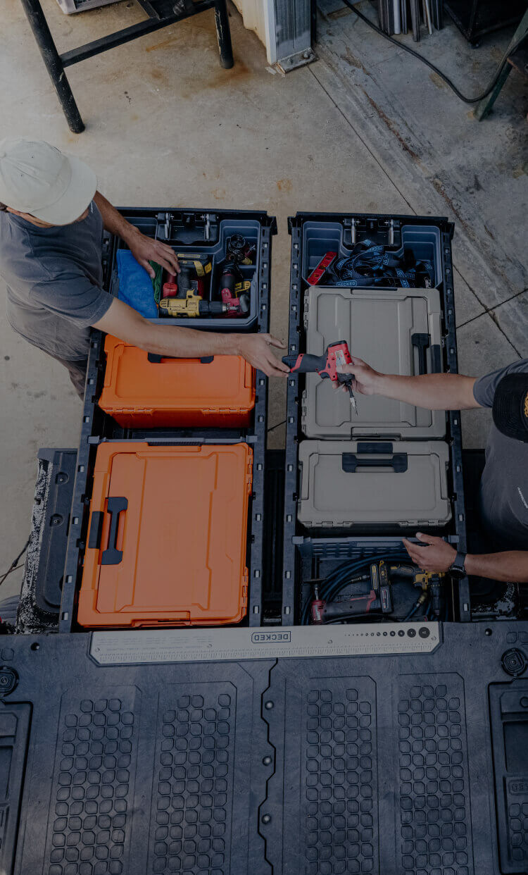 Two people organizing toolboxes in their DECKED Drawer System.