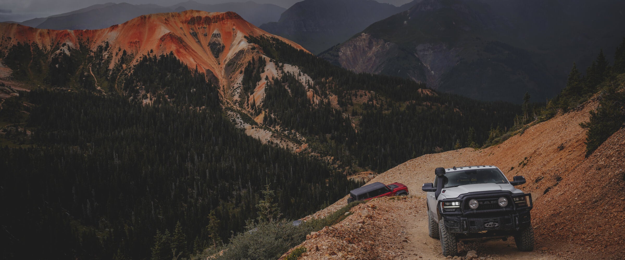 two trucks driving up a steep mountain road