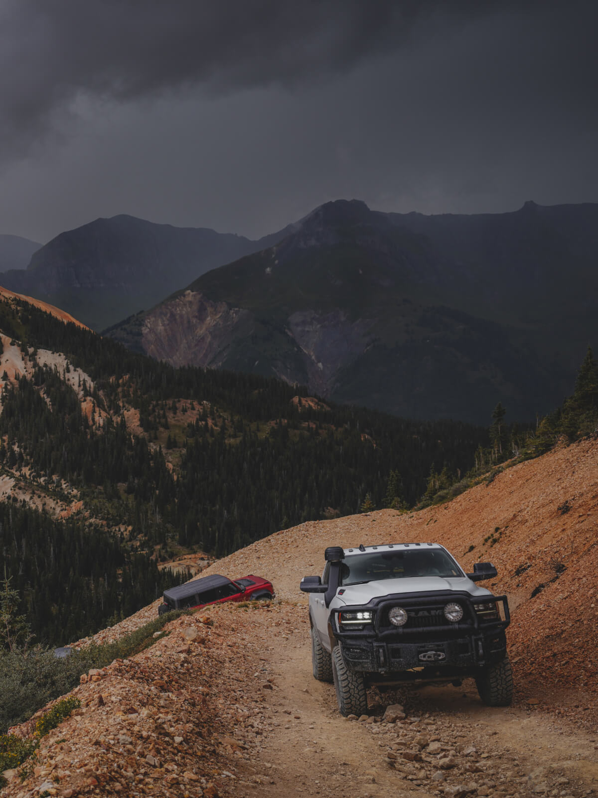 two trucks driving up a steep mountain road