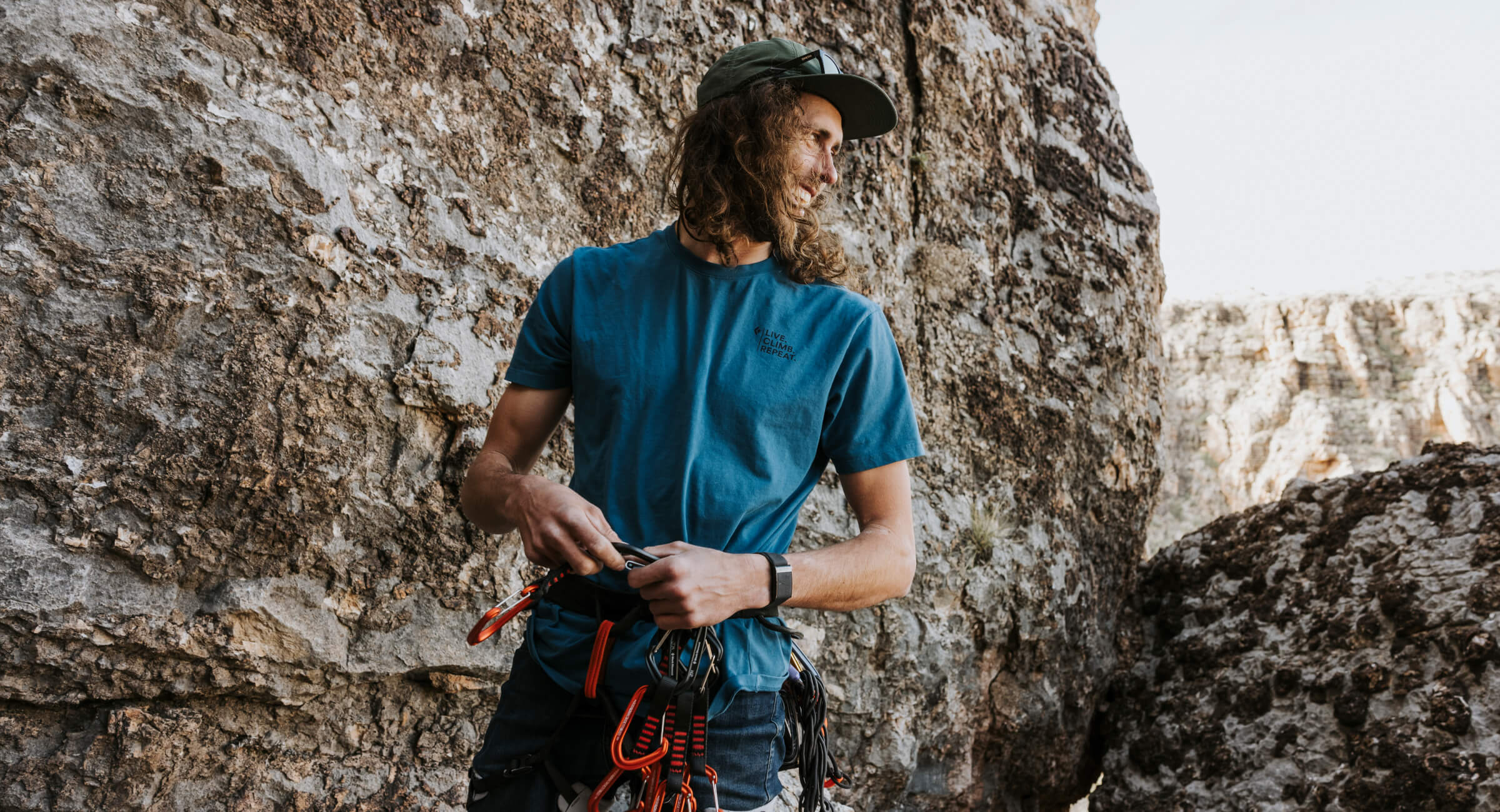 Jackson in his climbing harness standing next to a rock wall.