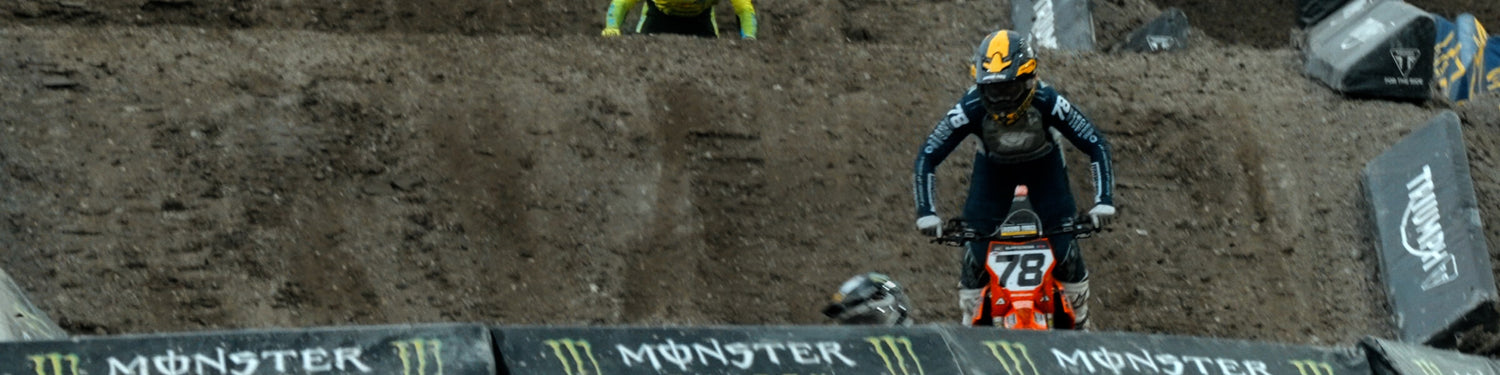 Motocross rider on a bike with 'Monster' branding in a dirt track setting