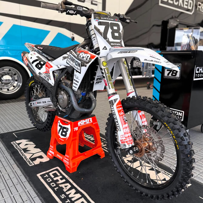 Motocross bike with number 78 on a stand at a racing event.