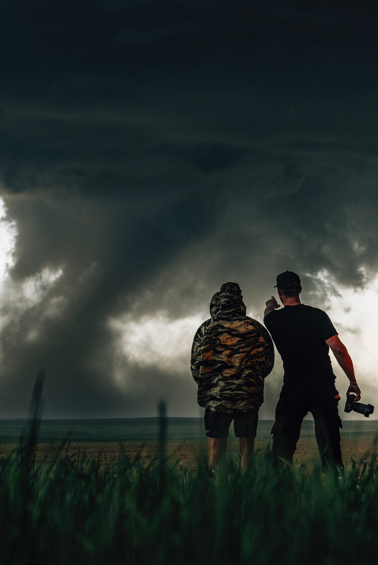 Danny Bolton and Ricky Forbes observing a tornado while standing while standing in a field.