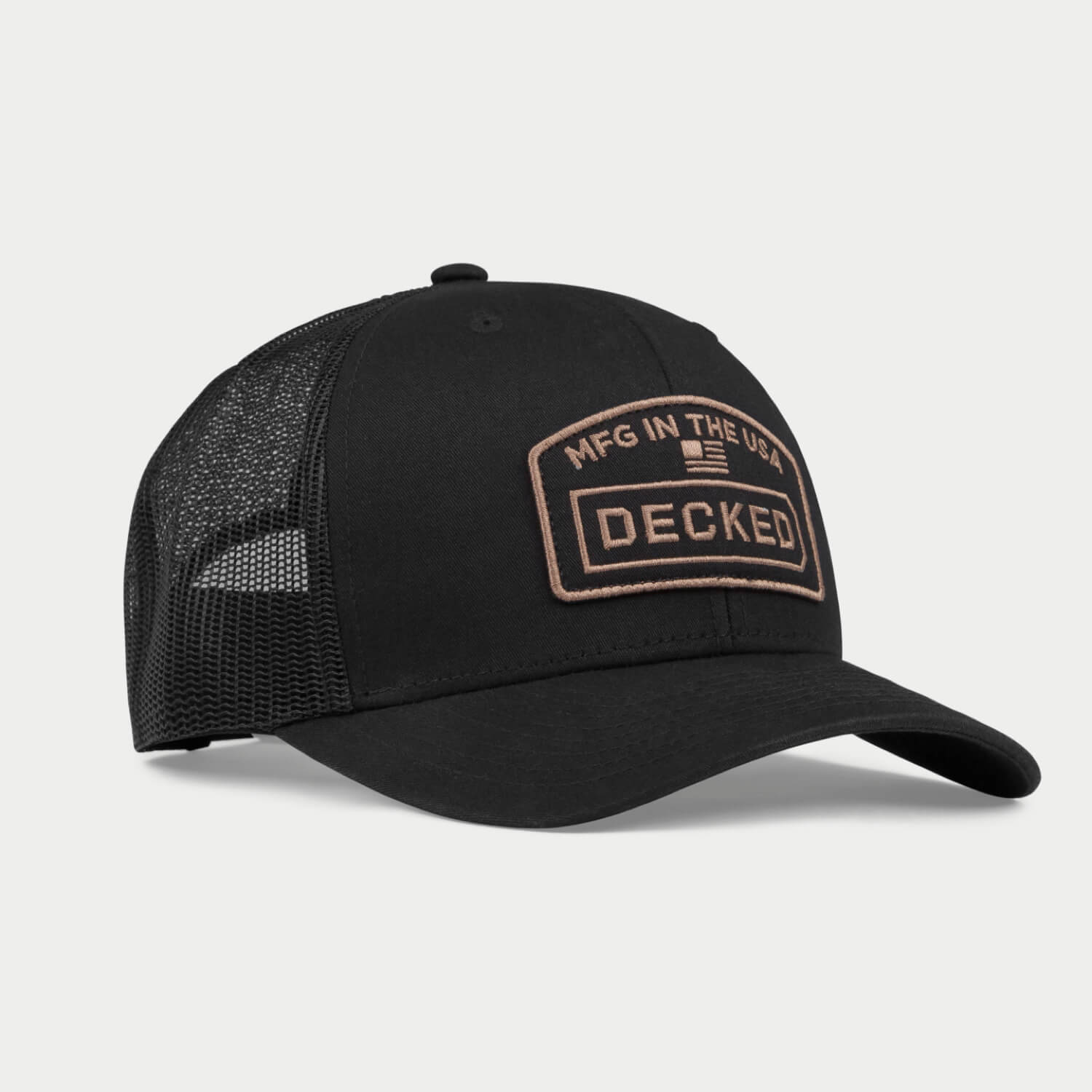 An angled black hat with a mesh back with a badge on it that has an embroidered "MFG in the USA", American Flag, and DECKED logo.