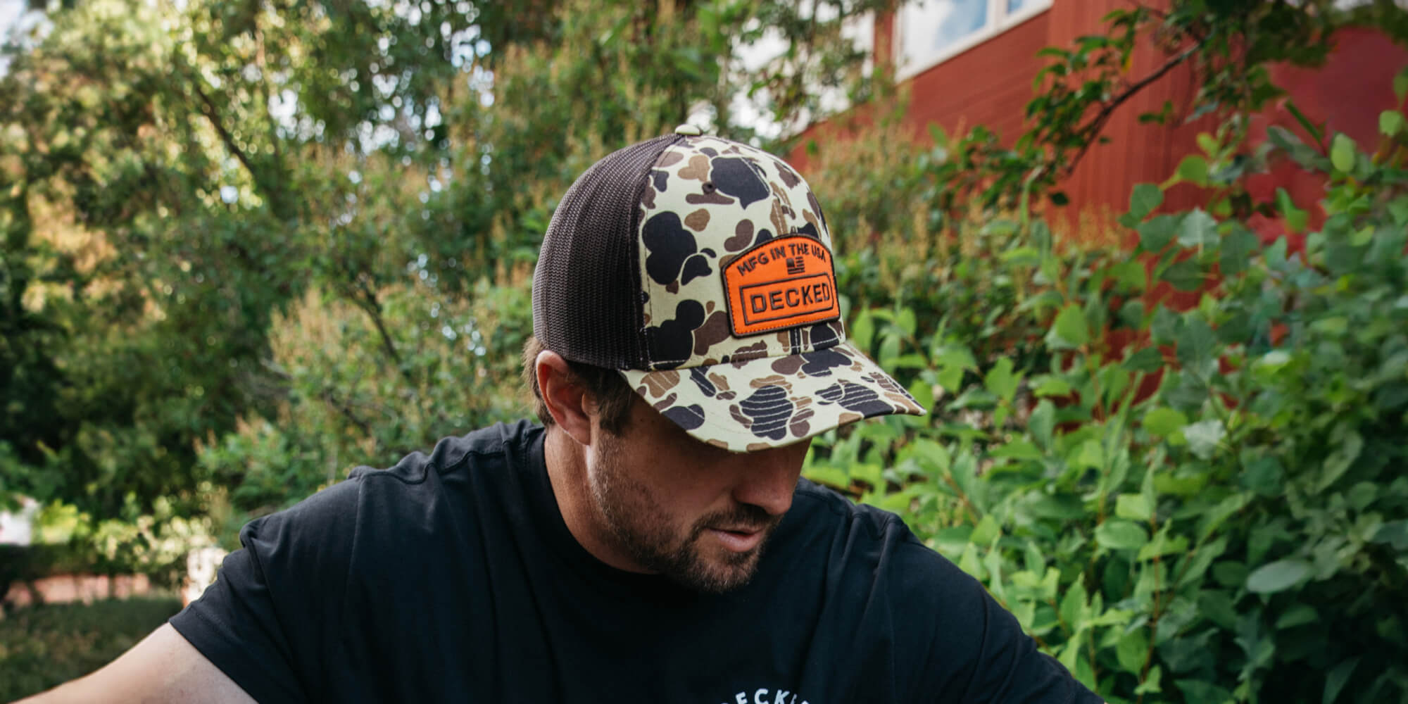Man wearing a camouflage cap with a DECKED logo outdoors