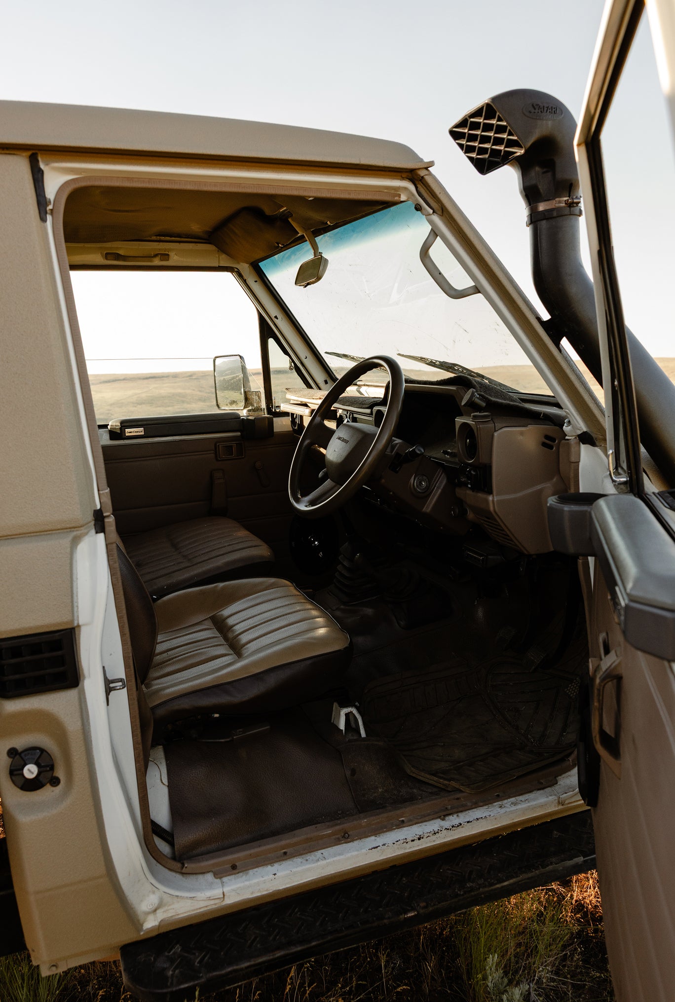 Interior view of a 1999 Toyota Land Cruiser, showing the driver and passenger seats, steering wheel, dashboard, and raised snorkel intake.