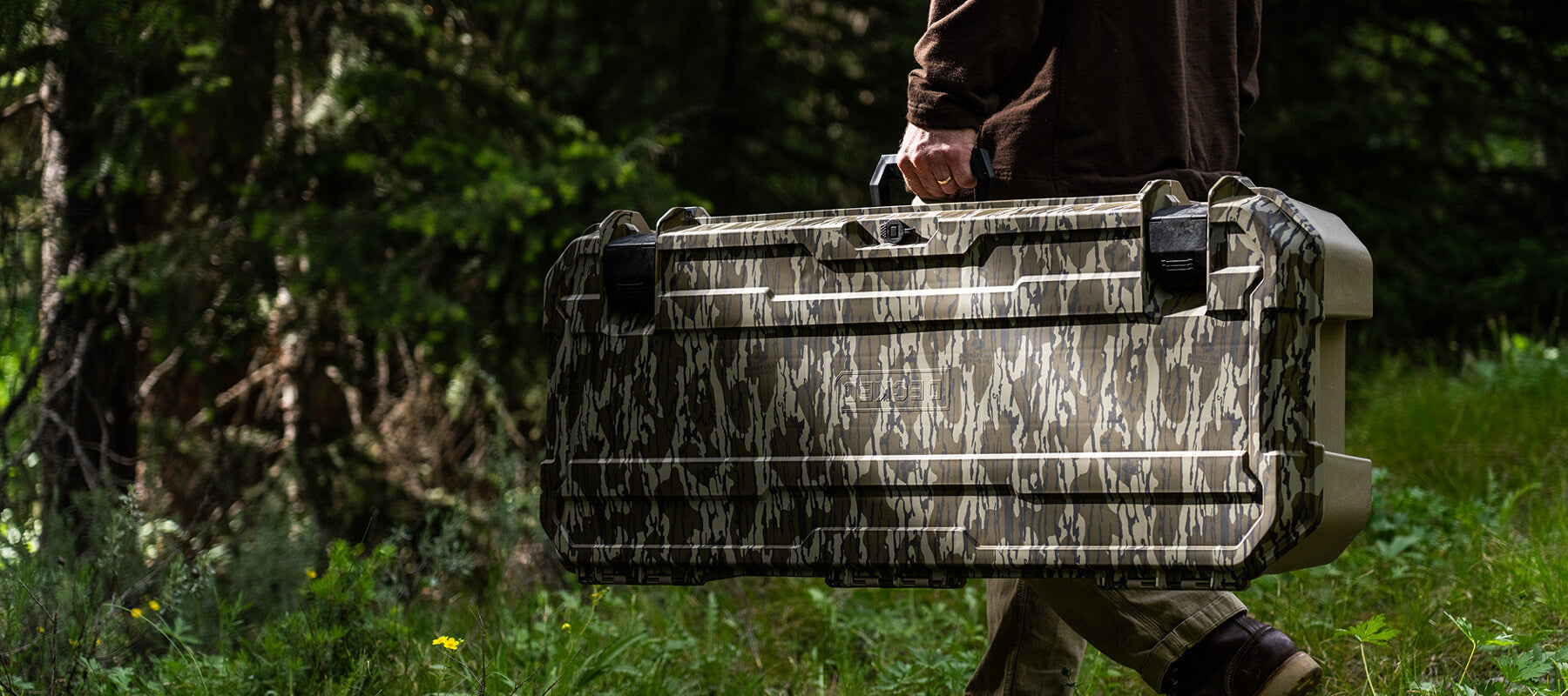A man carrying his Mossy Oak Honcho storage case in the woods.