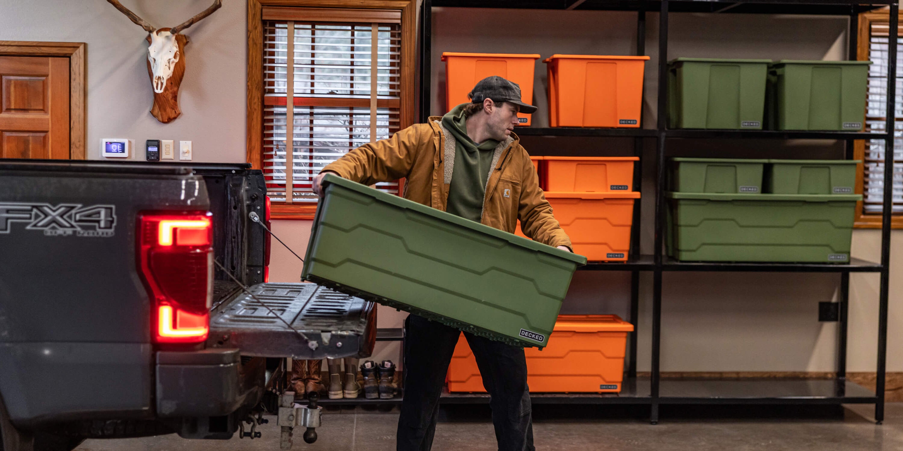 Person holding a green storage bin in front of a truck with shelves displaying various colored bins.