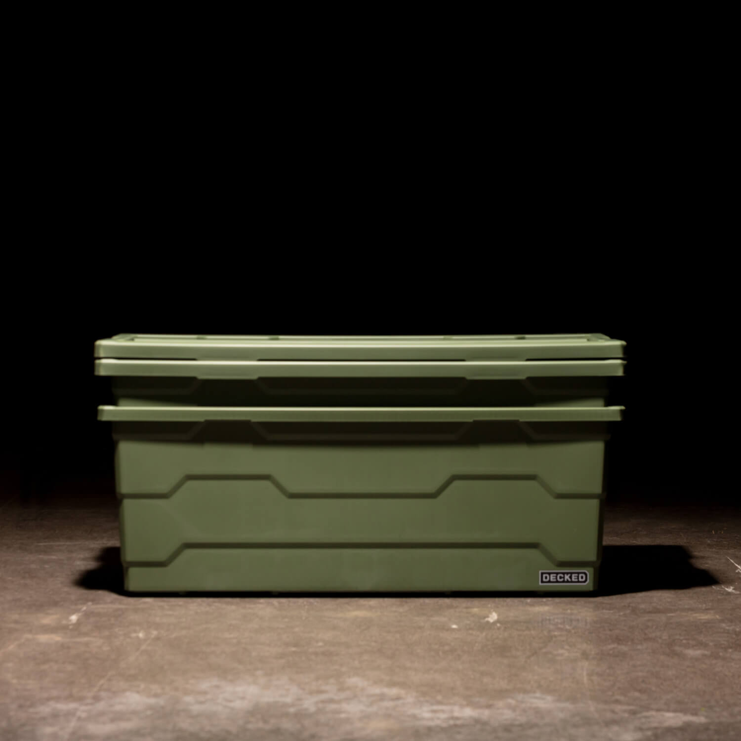 Two ranger green Payloader 133 Bins nested together with the lids sitting on top in a garage with a dark, shadowy background.
