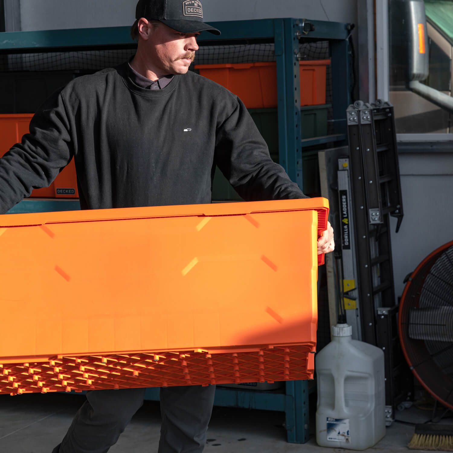 Man holding an orange Payloader 133 Bin in a garage setting