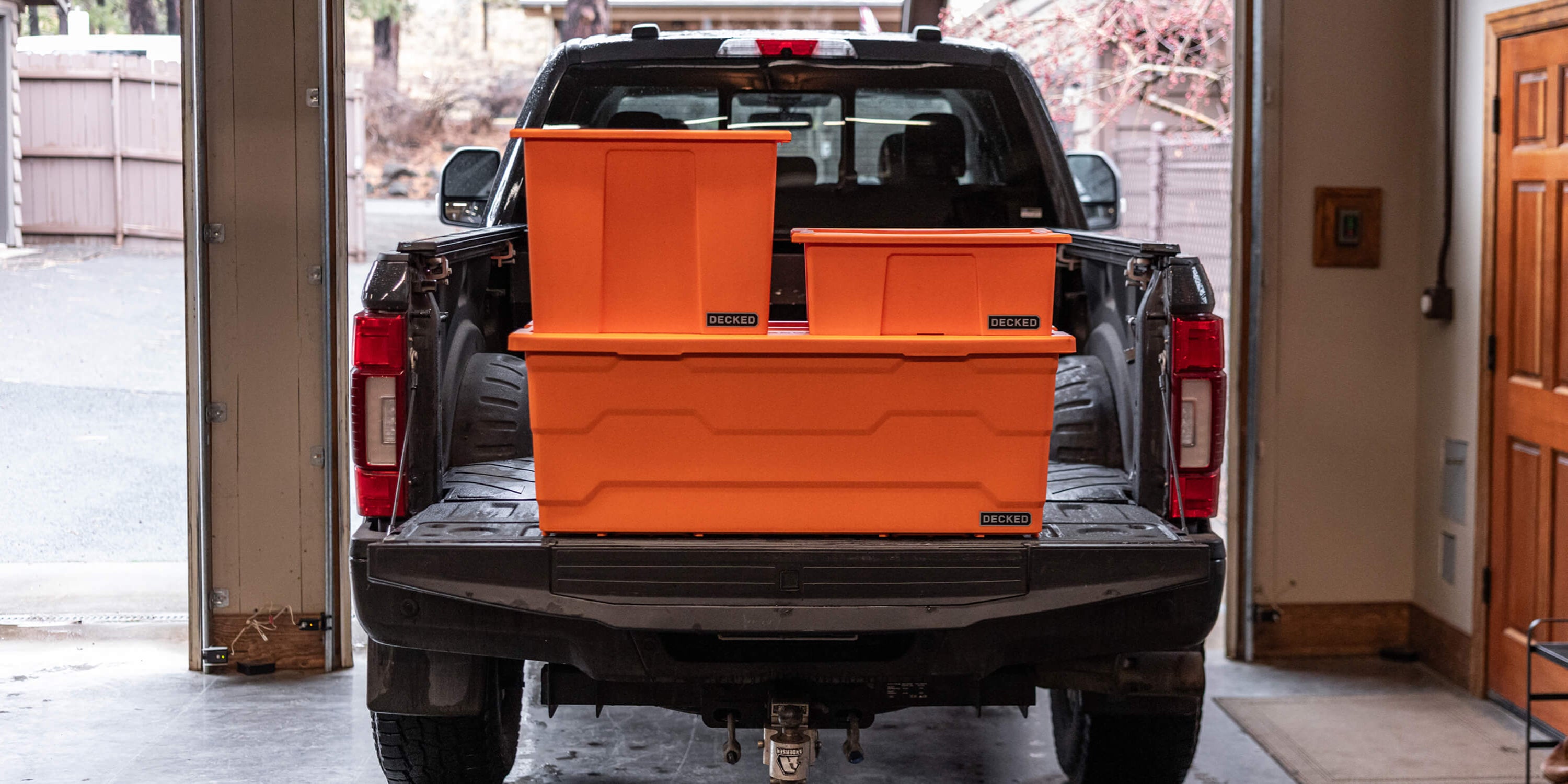 Truck bed with stacked blaze orange Payloader storage boxes in a garage setting