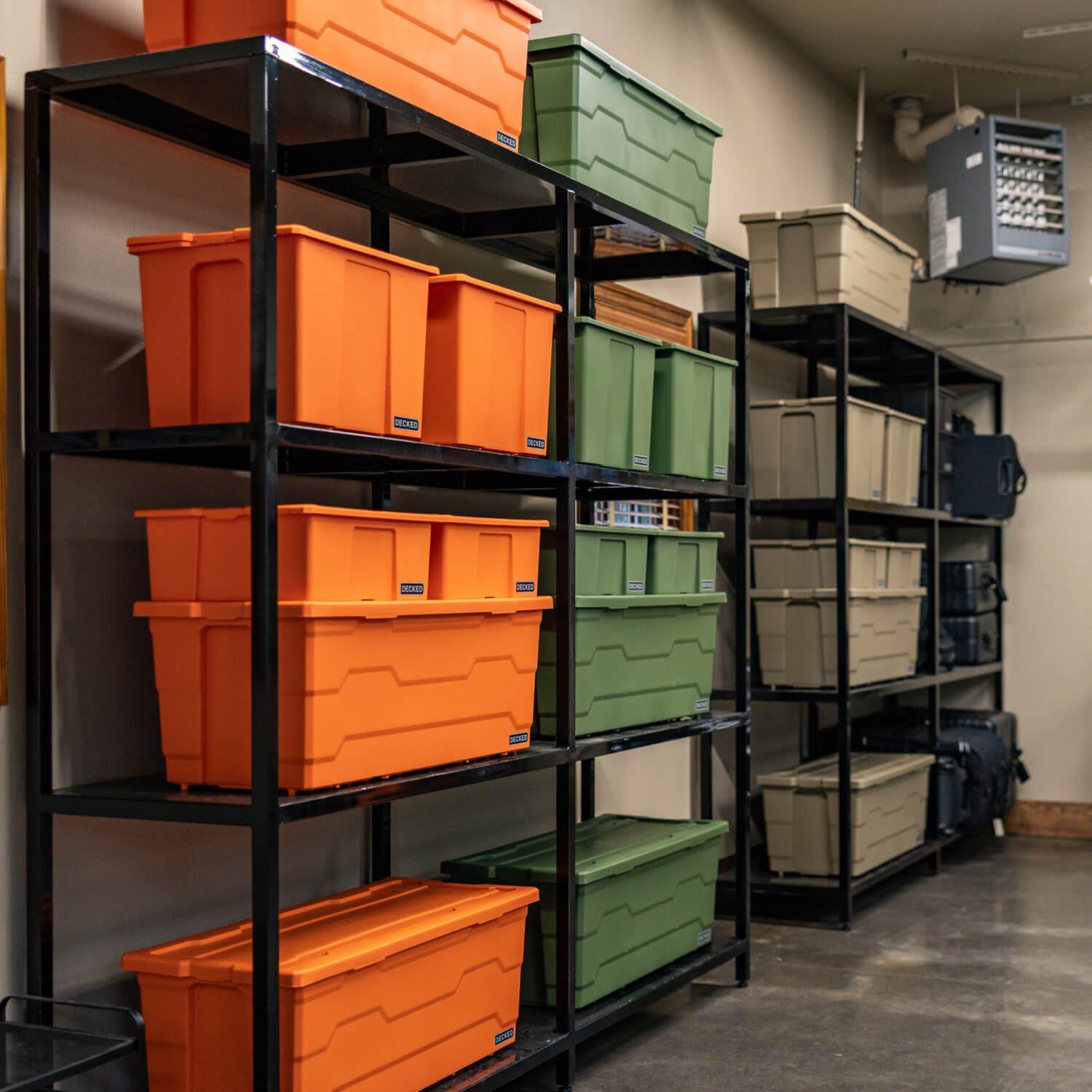 Storage shelves with assorted sizes of orange, green, tan and black Payloader storage bins in a garage.