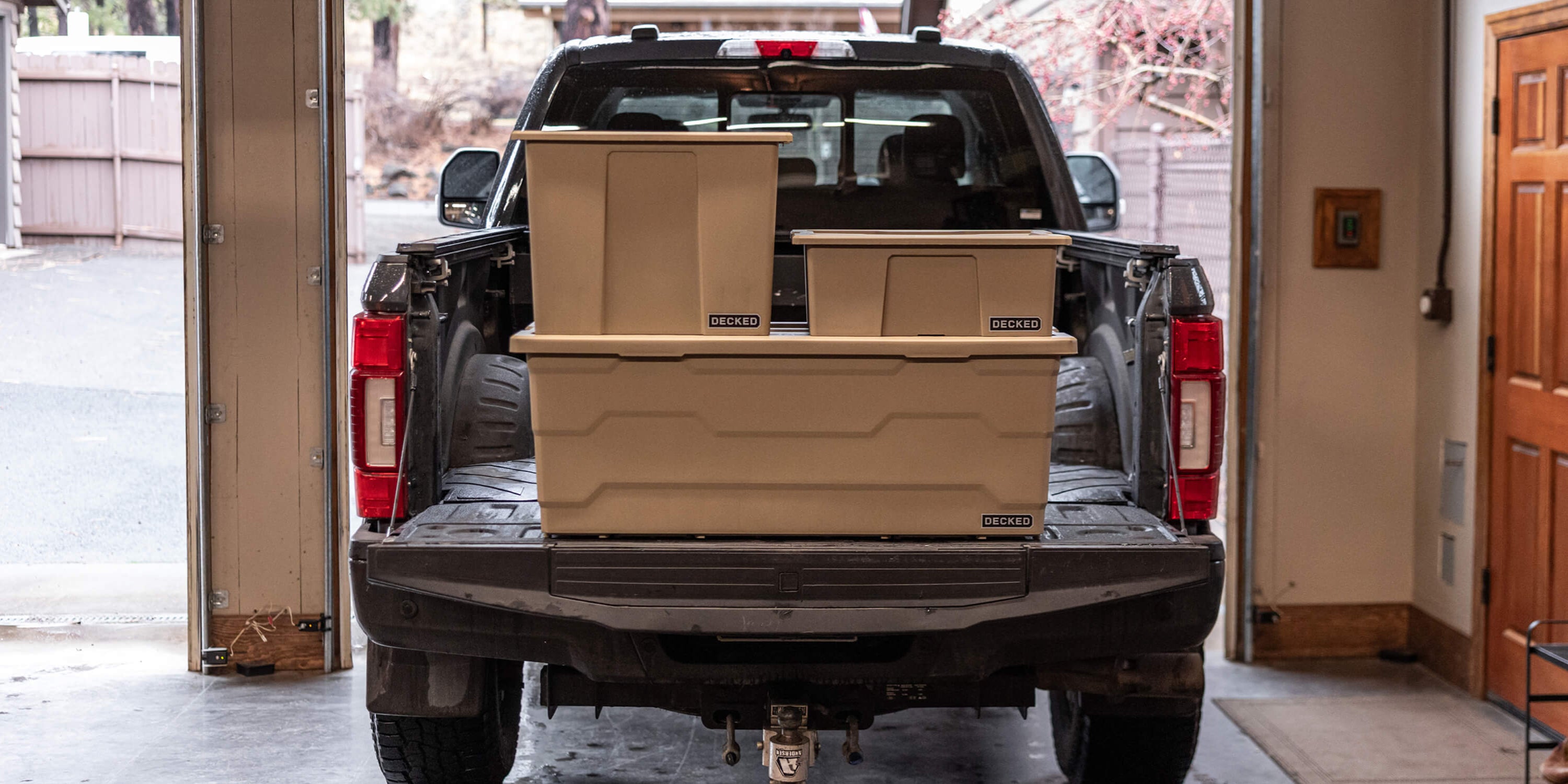 Truck bed with stacked desert tan Payloader storage boxes in a garage setting