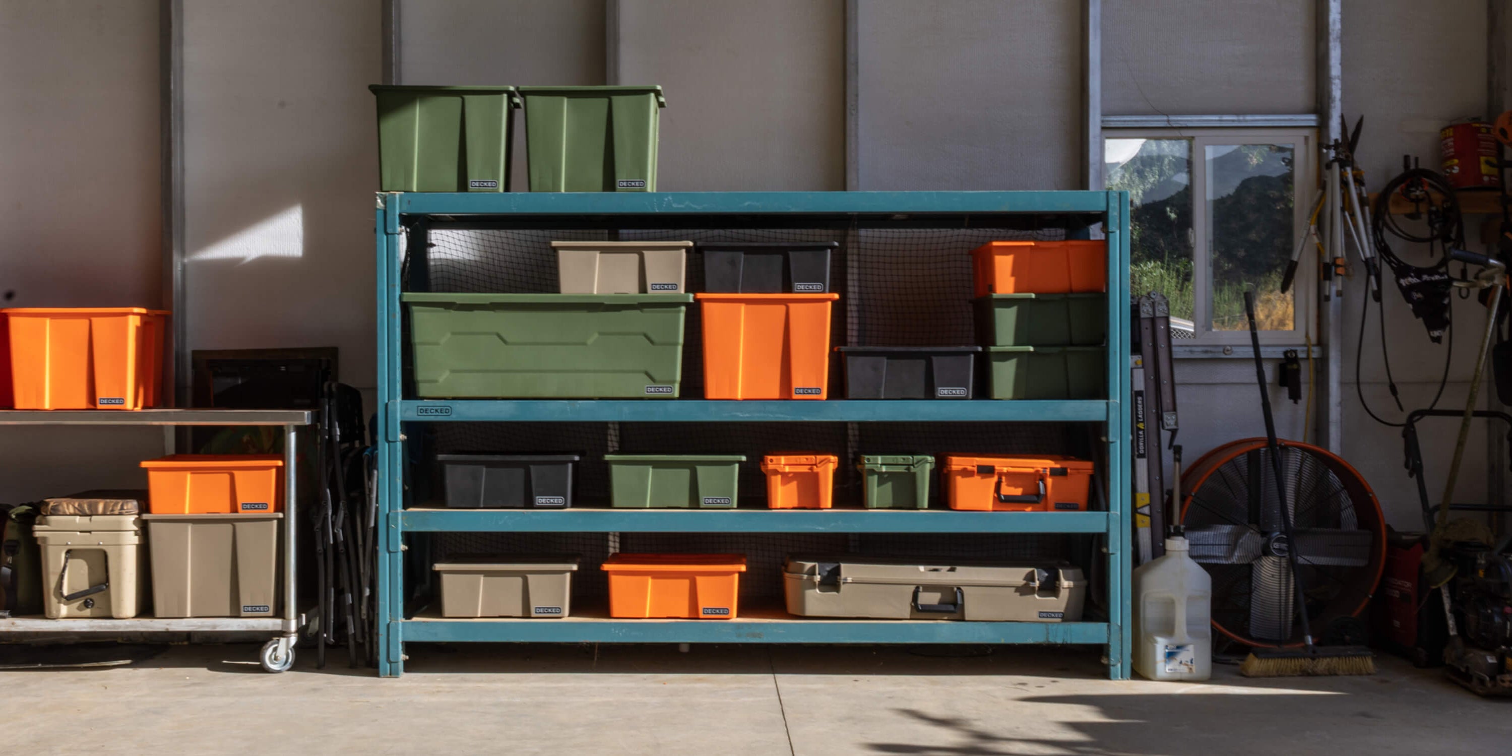 Storage rack with green, orange, black and tan DECKED Payloader Bins in a large garage.