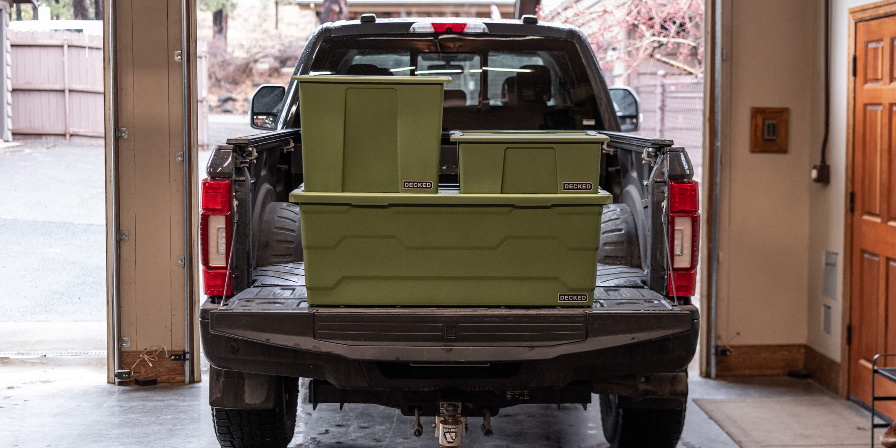 The three ranger green Payloader sizes stacked on the tailgate of a truck in a garage.
