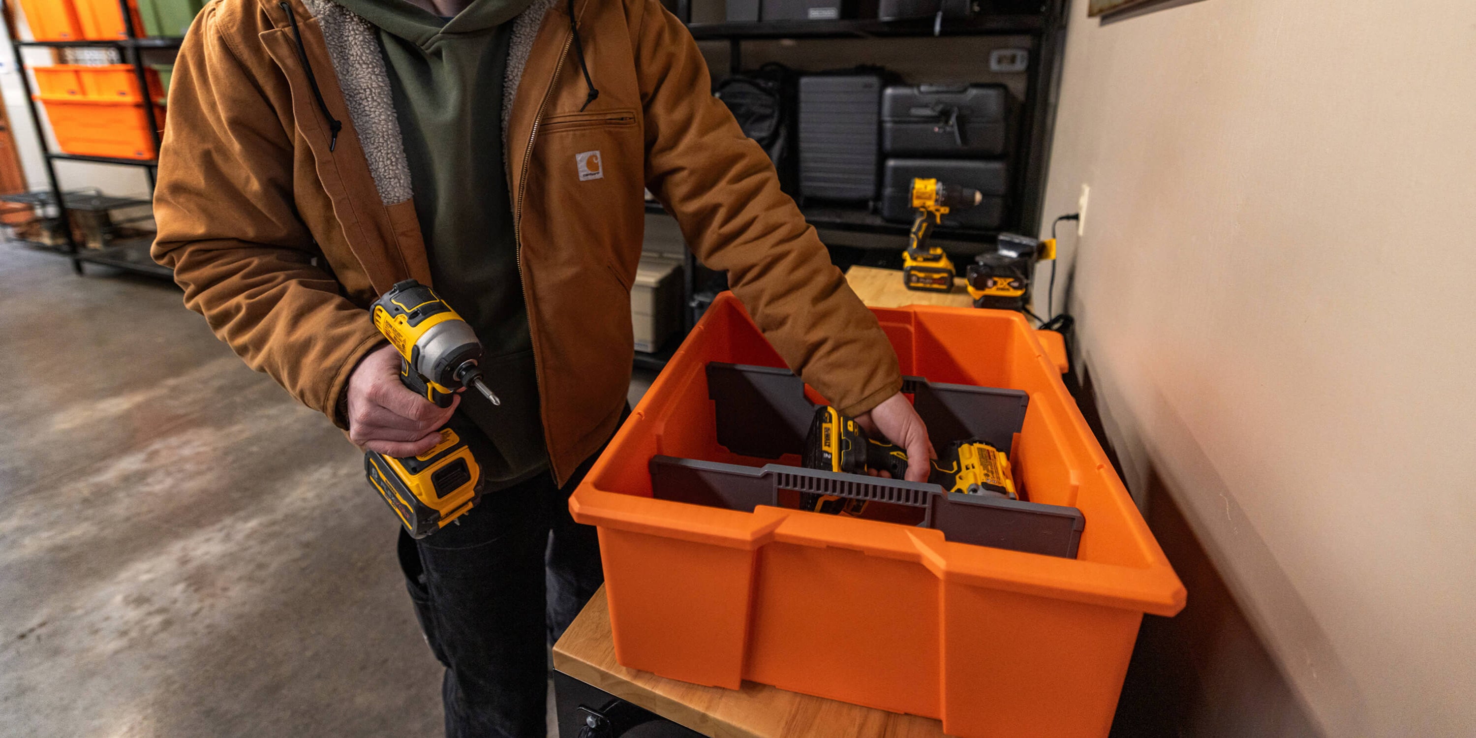 A man organizing power tools in his weatherproof and rugged blaze orange DECKED Payloader Bin.