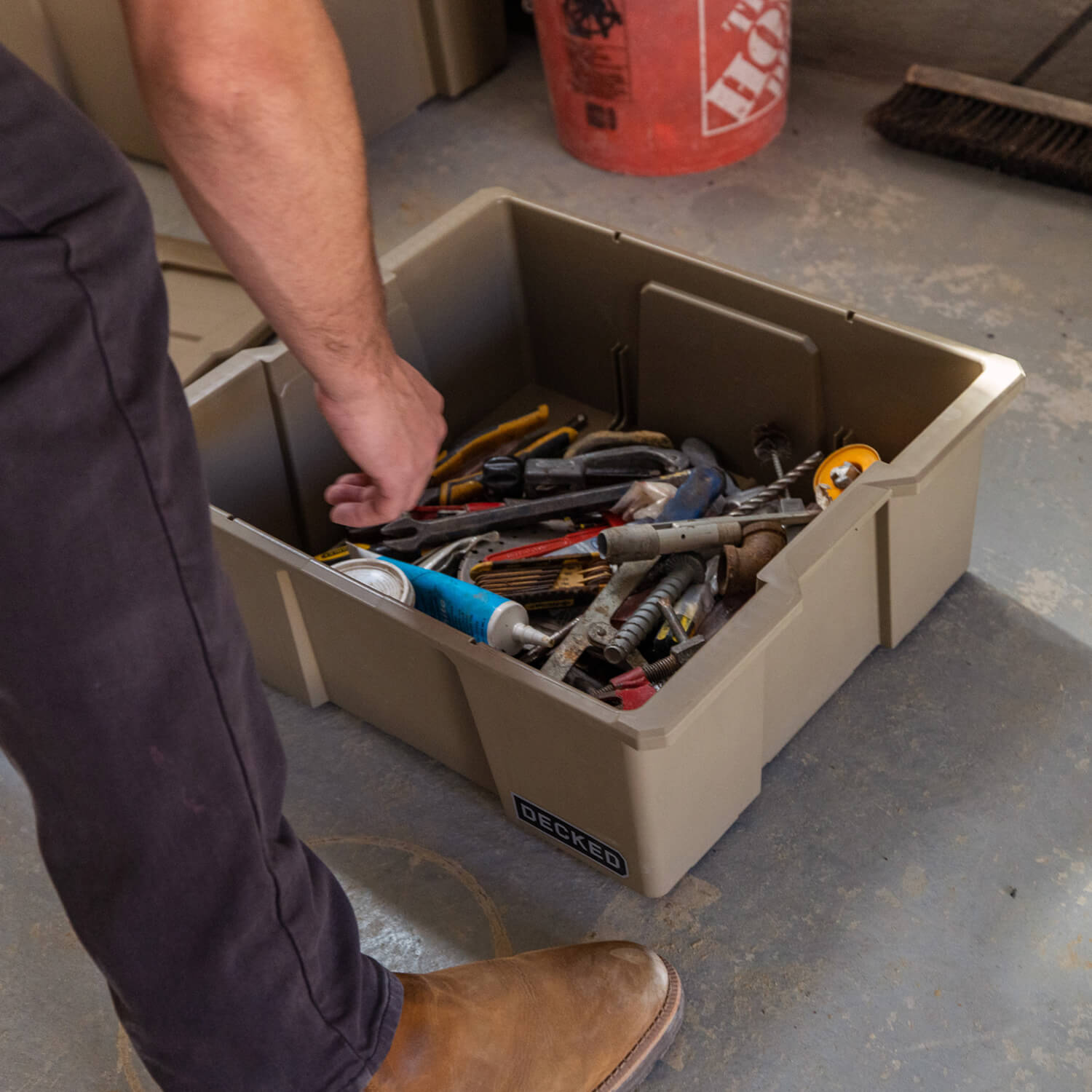 A man in his garage, organizing hand tools in a desert tan Payloader Bin.