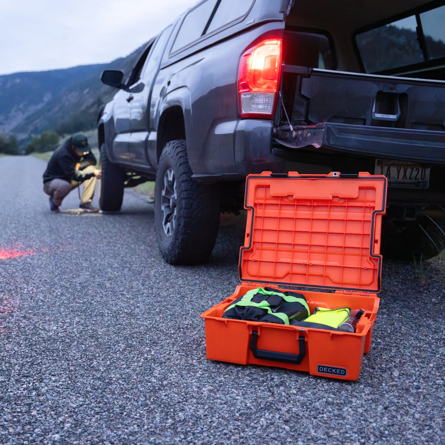 The Roadside OS Kit sitting open next to a truck, while the driver works on the front tire.