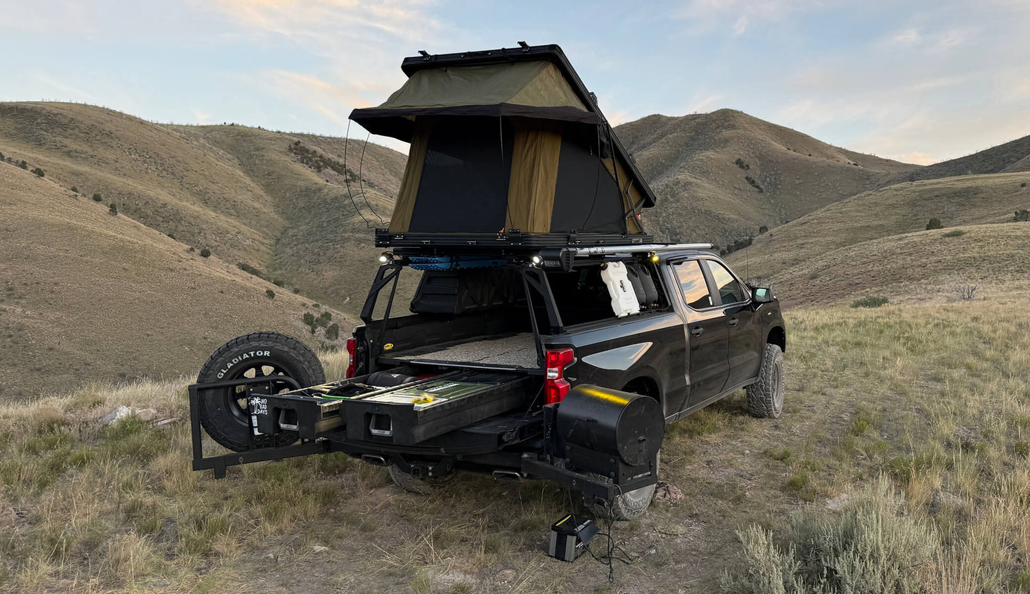 Black truck with a rooftop tent in a desert landscape