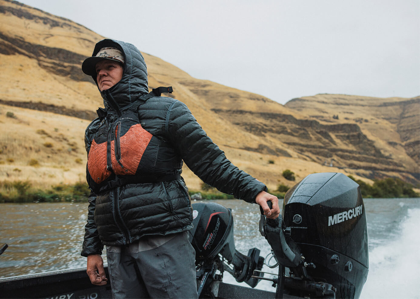 Curtis on a boat with a Mercury outboard motor in a mountainous landscape