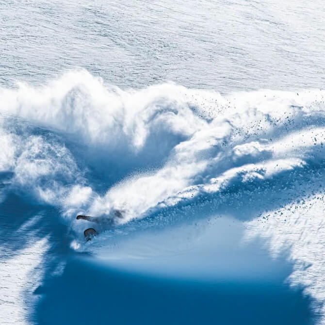 Curtis snowboarding, the snow he is spraying almost looks like he is riding a large wave in the ocean