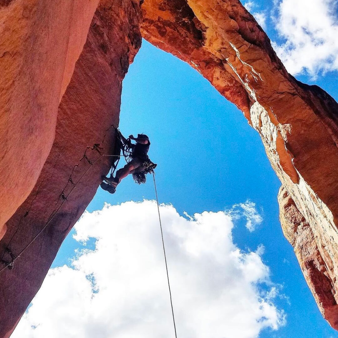 Jackson Marvell climbing an arch in the red rocks.