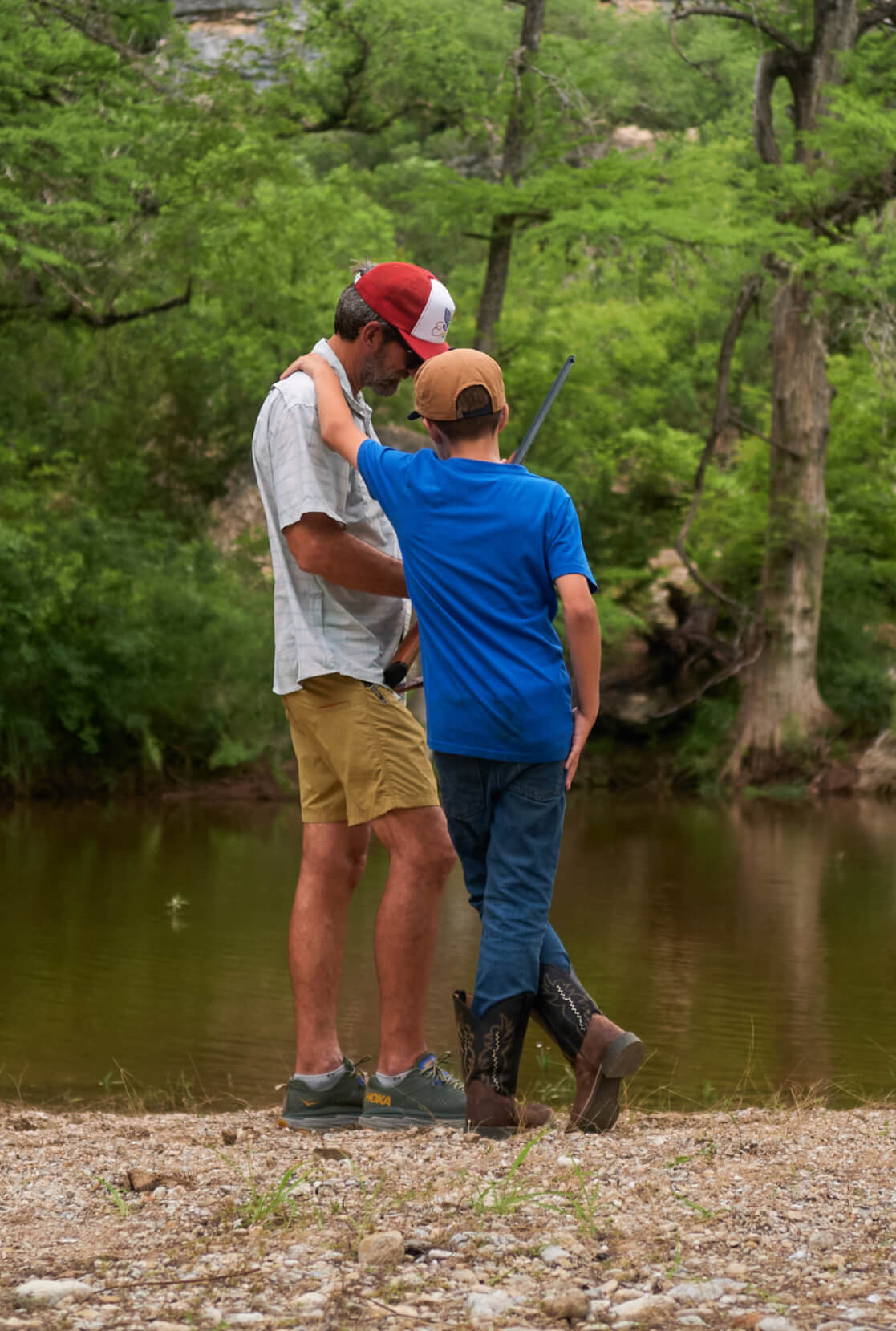 JT VanZant and his son standing on the side of a river.