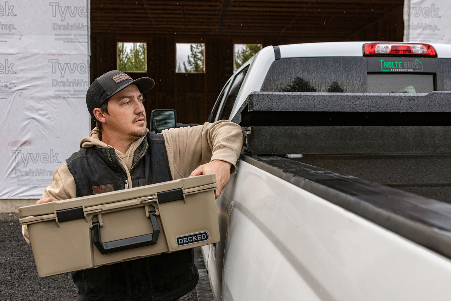 Man hoisting a DECKED D-co storage case into the Tool Box, using his elbow to hit the START Button that opens the Tool Box with ease.