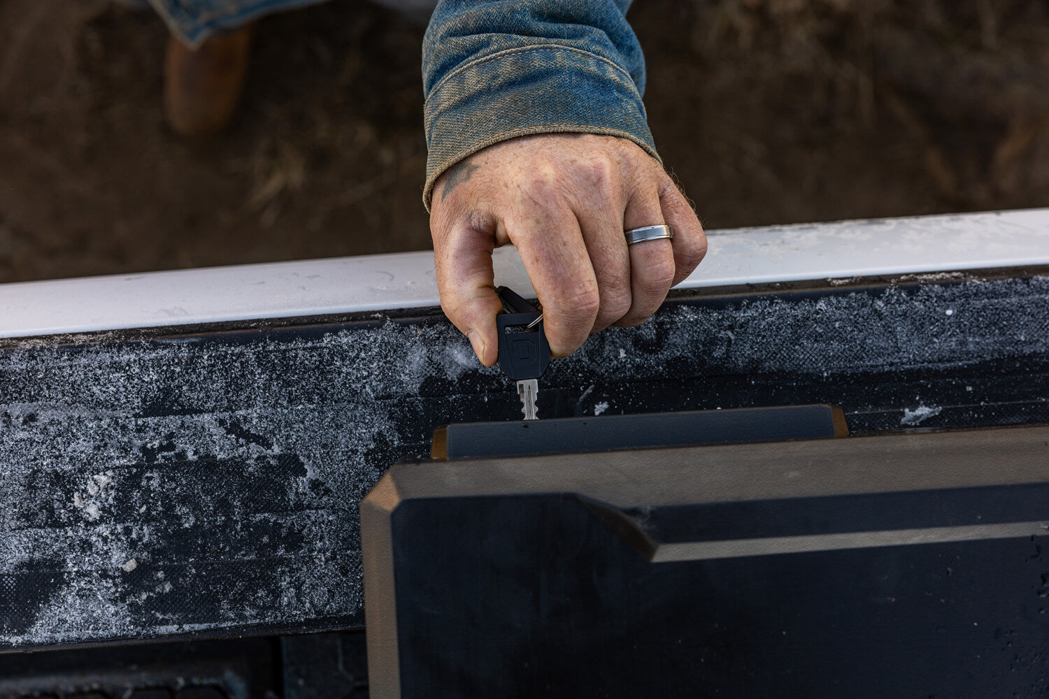 Hand using a key to open up the DECKED truck bed tool box on a frosty morning.