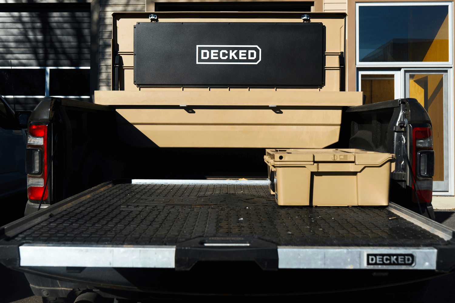 Open tan DECKED toolbox in the bed of a truck with a CargoGlide mounted.
