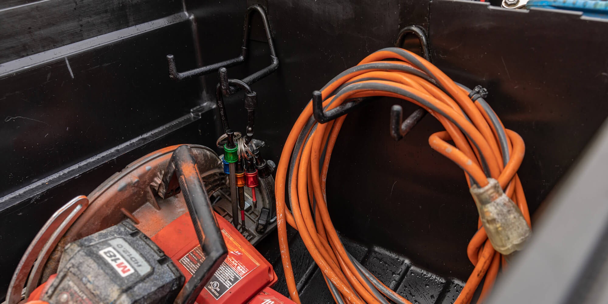 Orange extension cord coiled, hanging on a Tool Hook inside the Tool Box.