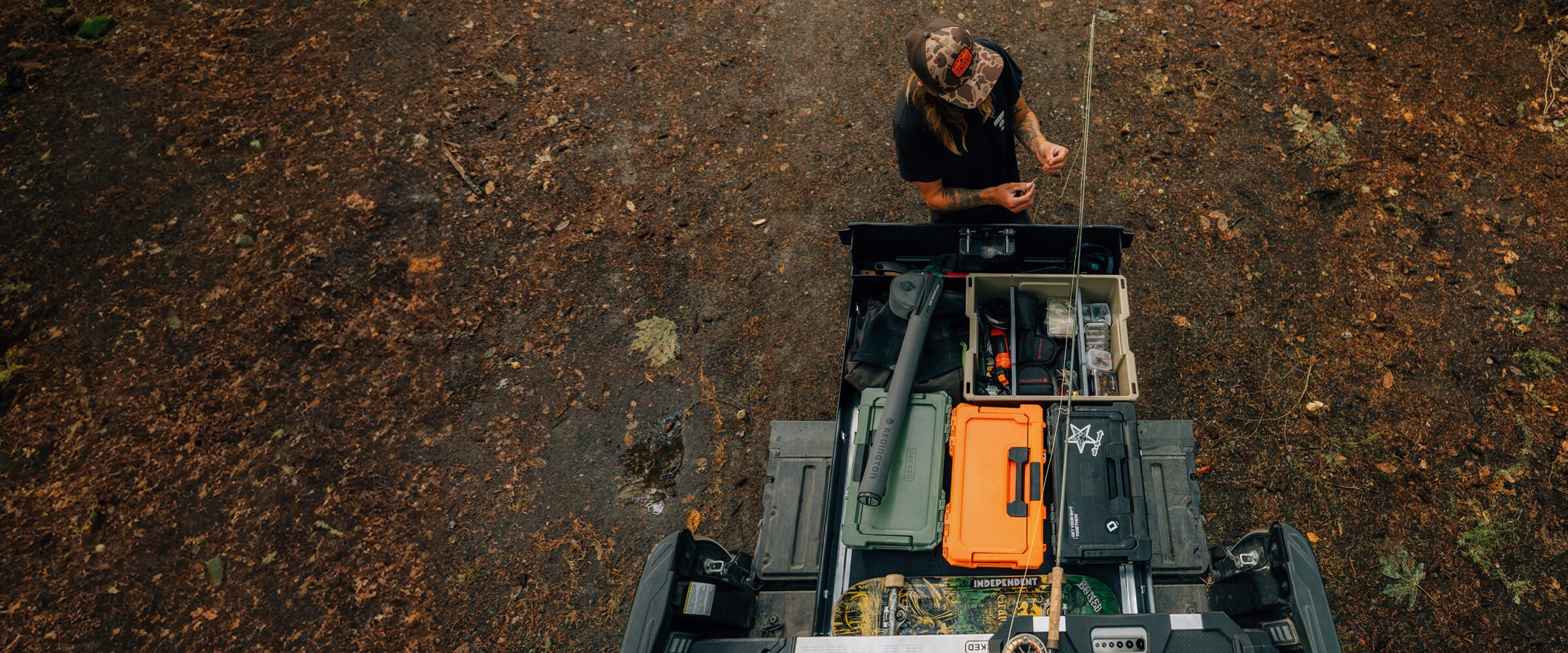 Person standing on a vehicle with open Drawer System with tackle boxes inside on a rough terrain